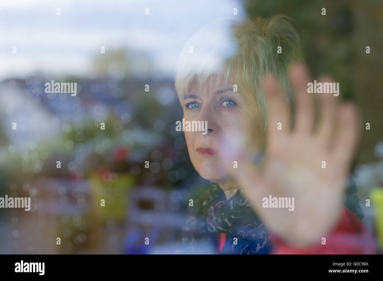 Nachdenklich Senior Blick durch eine Glasscheibe. Stockfoto