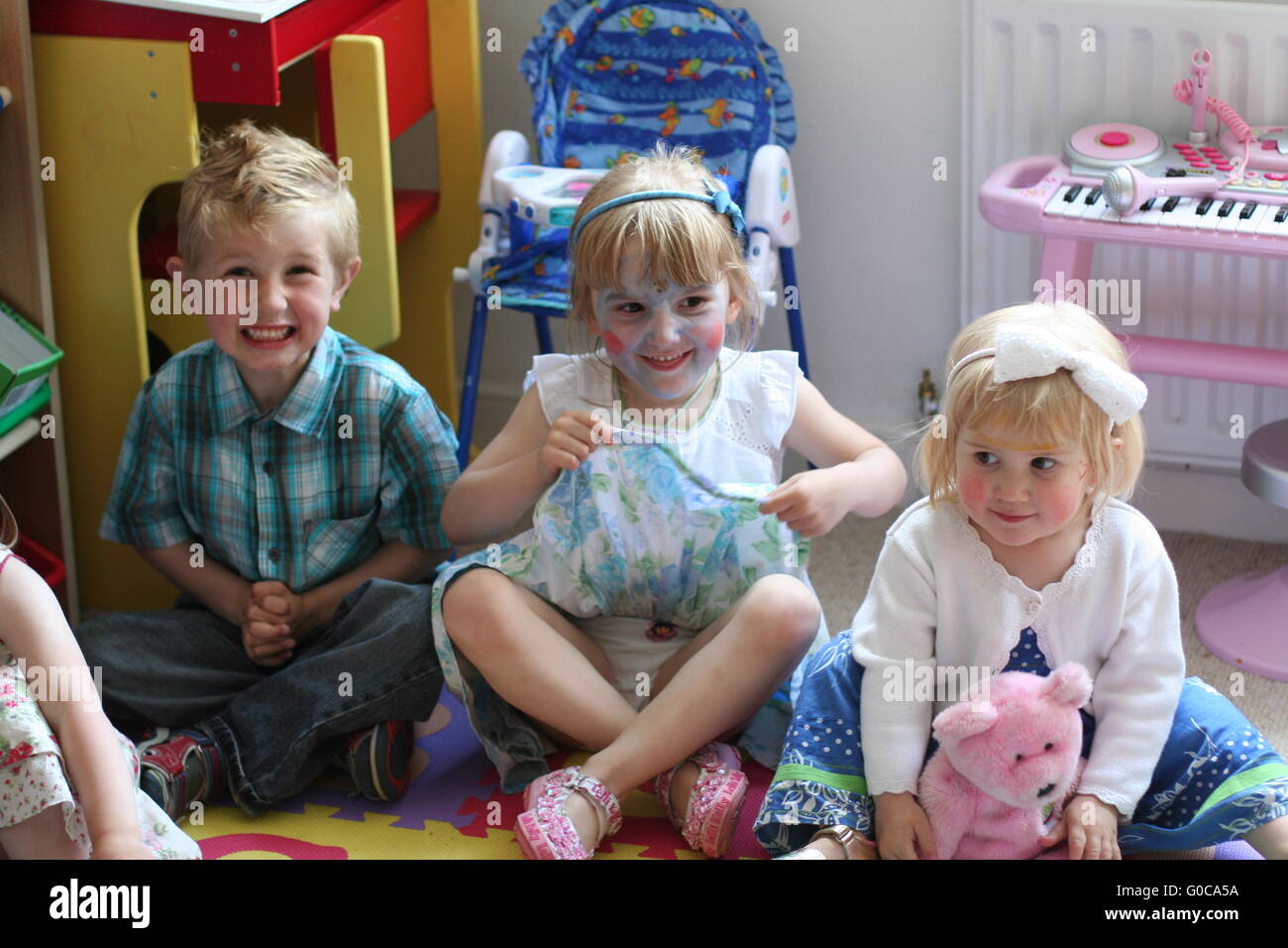 Eine Gruppe Kinder sitzen gemeinsam tragen Gesicht Farbe an einem für Kinder, Kindergeburtstag, glückliche Kinder, Spaß Konzept, unschuldig, Unschuld Stockfoto