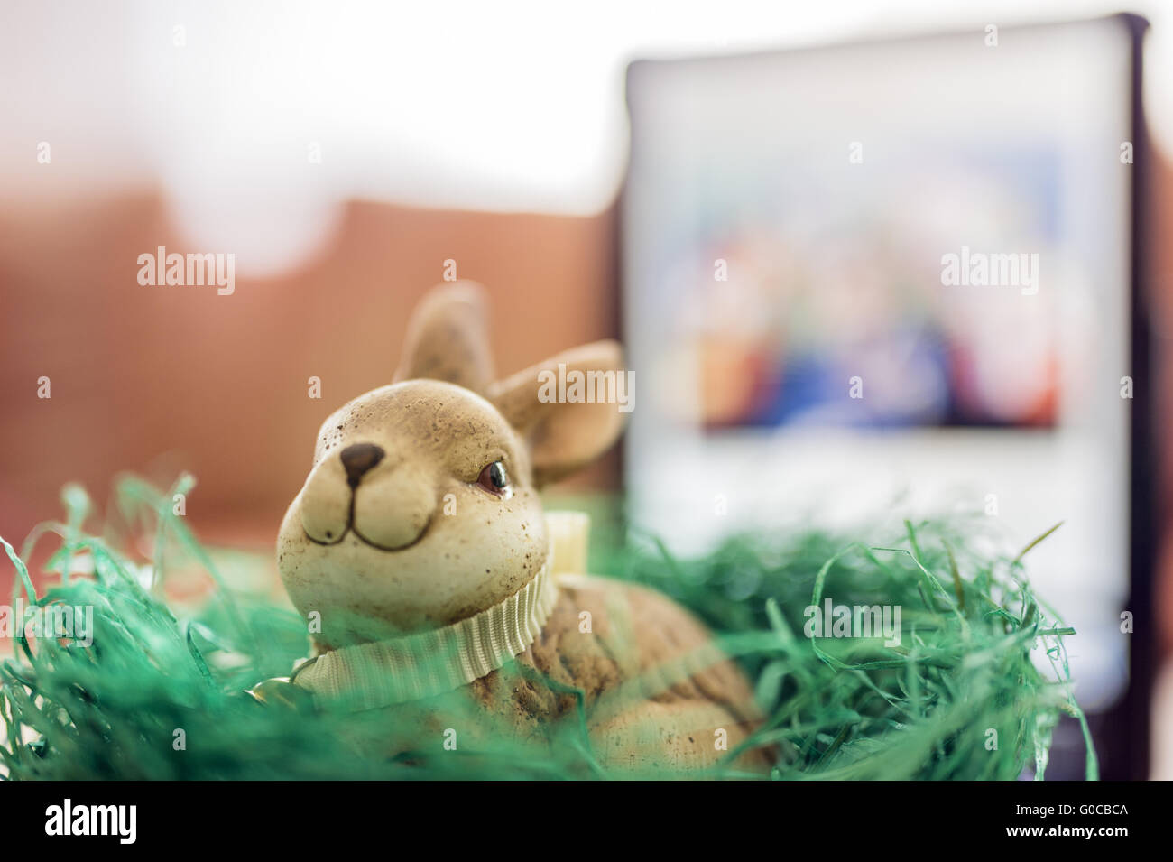 Ein Osterhase sitzt vor einem Tablet in einem Stockfoto