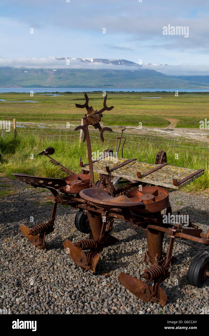 Island, Akureyri. Historische Rasen Häuser von Laufás. Oldtimer Landmaschinen mit malerischen Fjord in der Ferne. Stockfoto