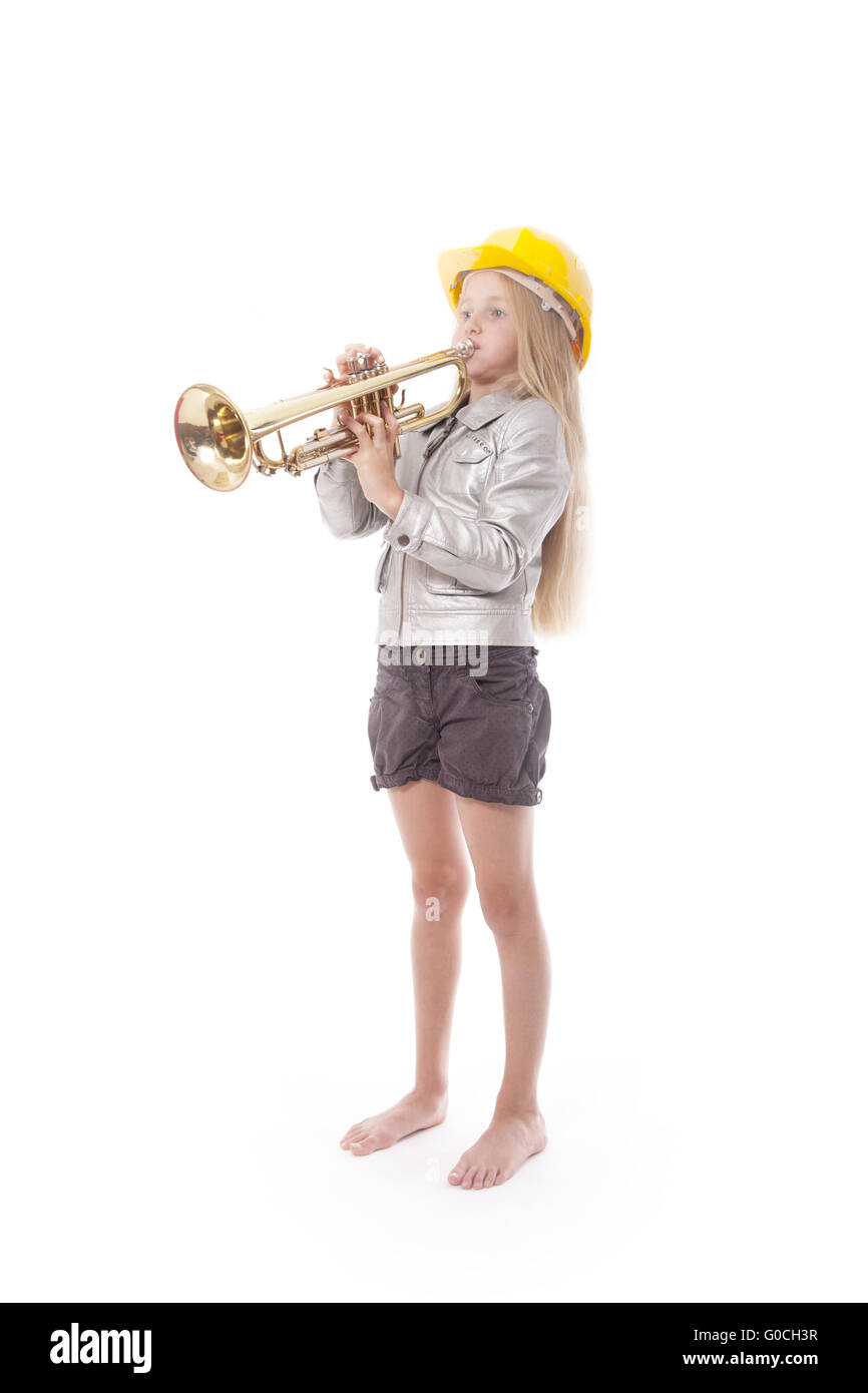 junges Mädchen mit gelben Helm spielt Trompete im Studio vor weißem Hintergrund Stockfoto