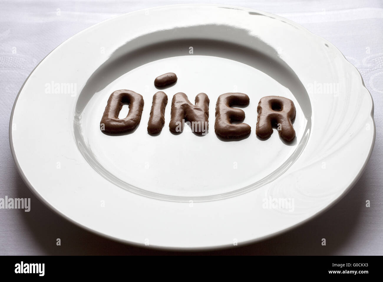 Buchstaben, das Wort Díner auf einem Teller Stockfoto