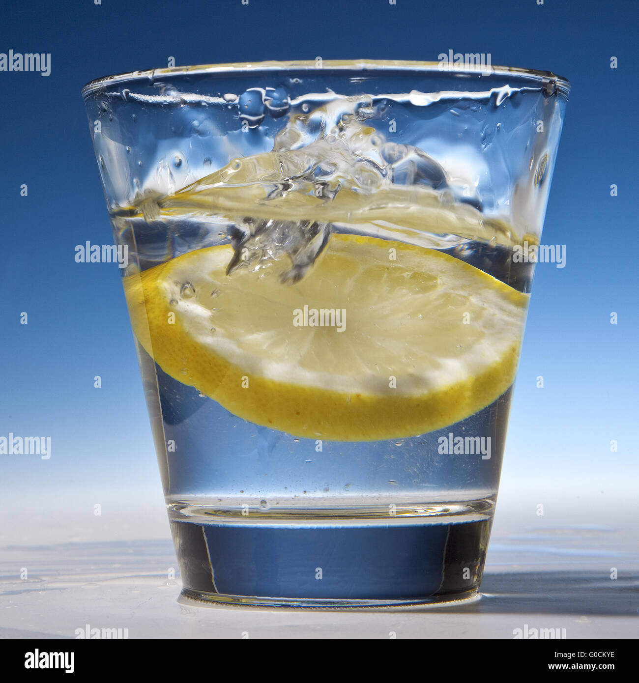Scheibe der Zitrone in ein Glas mit Wasser fallen Stockfoto