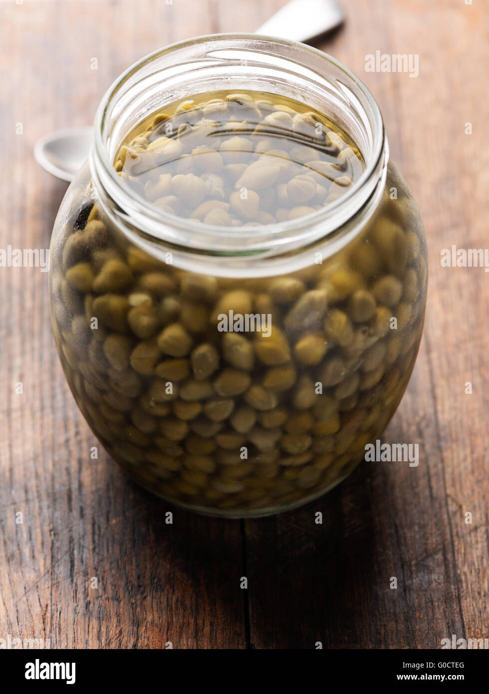 Kapern in Glas auf hölzernen Hintergrund closeup Stockfoto