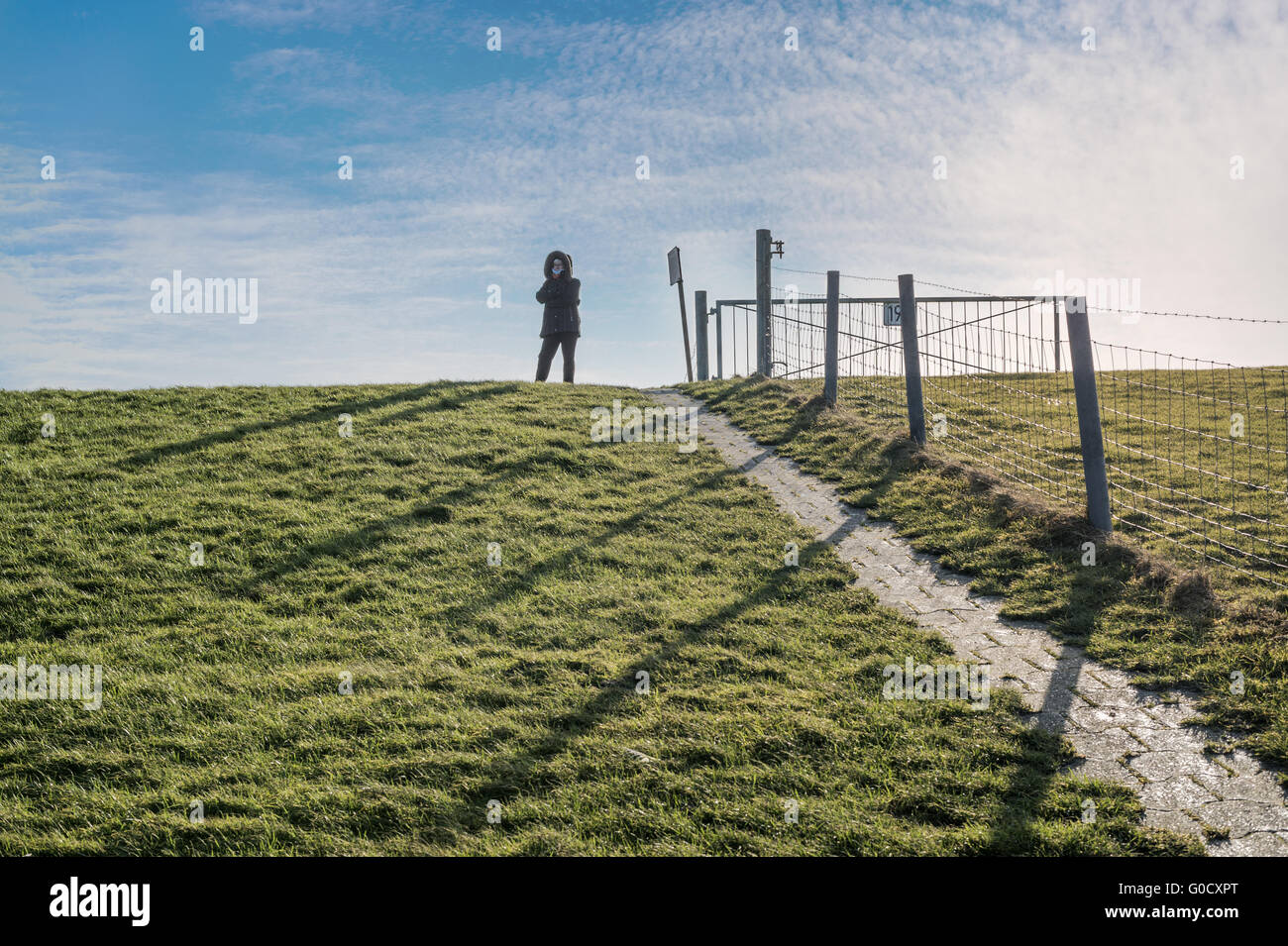 Einsame Frau auf dem Deich an der Nordseeküste. Stockfoto
