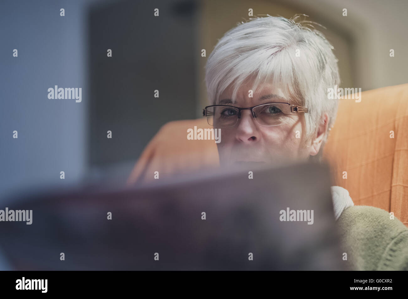 Ein Senior-Frau im Sessel sitzen, auf der Suche nach ove Stockfoto