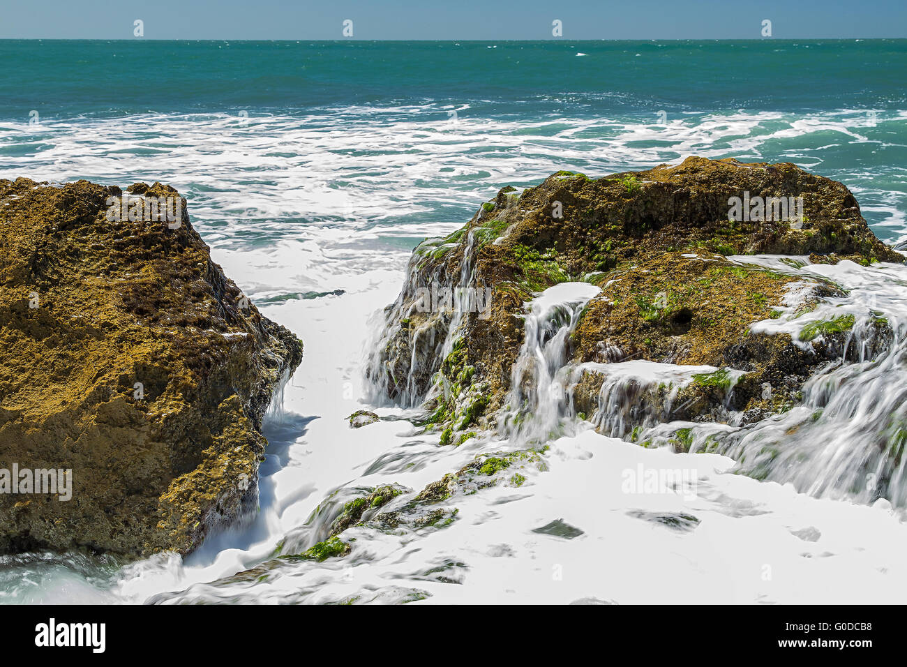Türkis, rollende Welle knallte auf den Felsen. Stockfoto