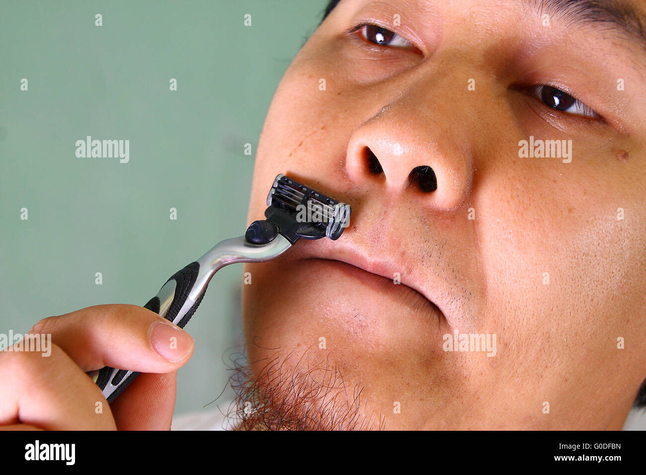 Junge asiatische Mann rasiert seine Haare im Gesicht ohne Sahne Stockfoto