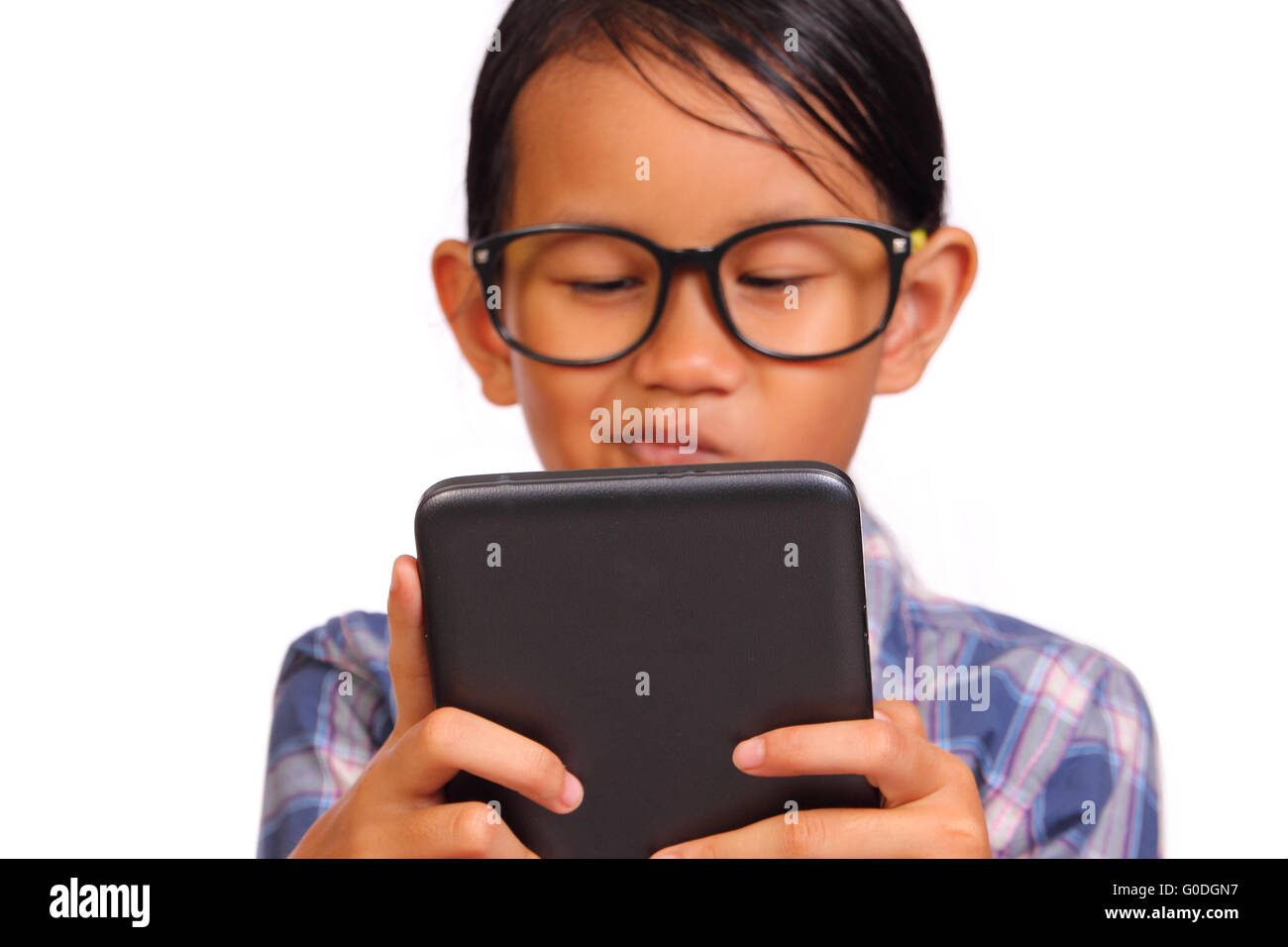 Kleines Mädchen mit Brille ernsthaft spielen ihr Tablet isoliert auf weiss Stockfoto