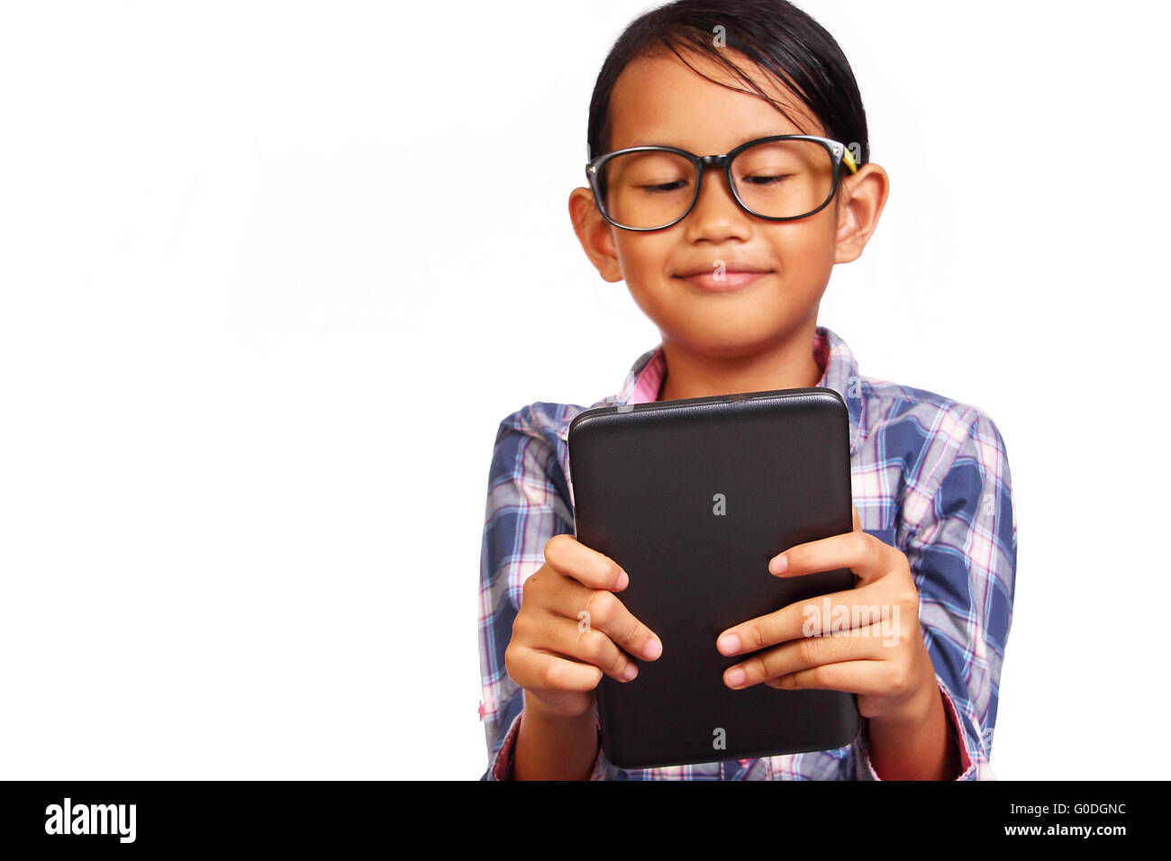 Kleines Mädchen mit Brille Lächeln während der Suche ihr Tablet isoliert auf weiss Stockfoto