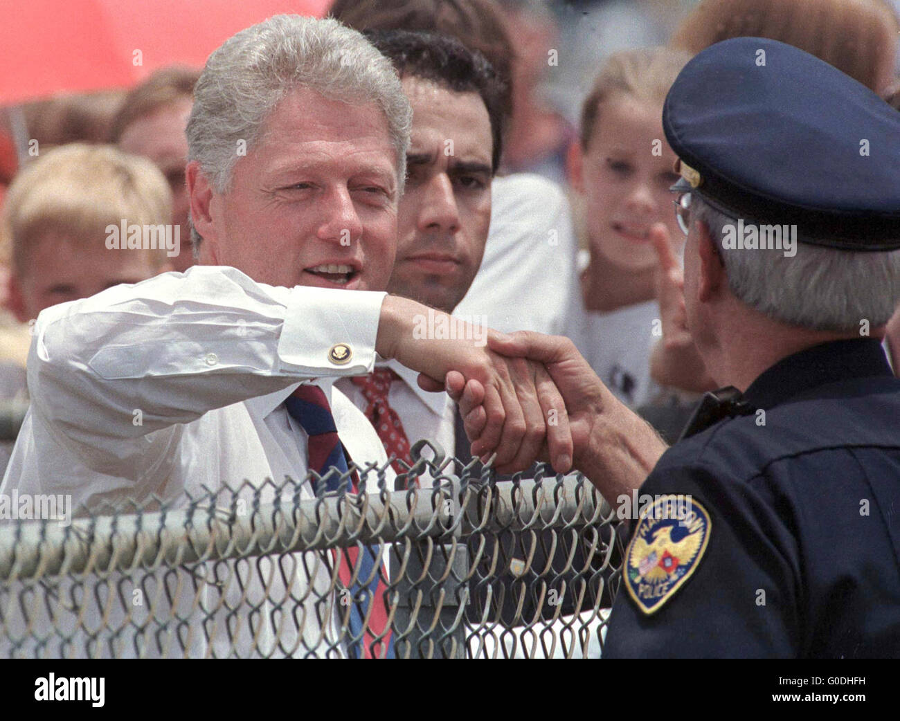US-Präsident Bill Clinton schüttelt die Hand über einen Zaun mit einer Harrison Stadt Polizist während eines Besuchs in Boone County, Arkansas. 1997. Stockfoto