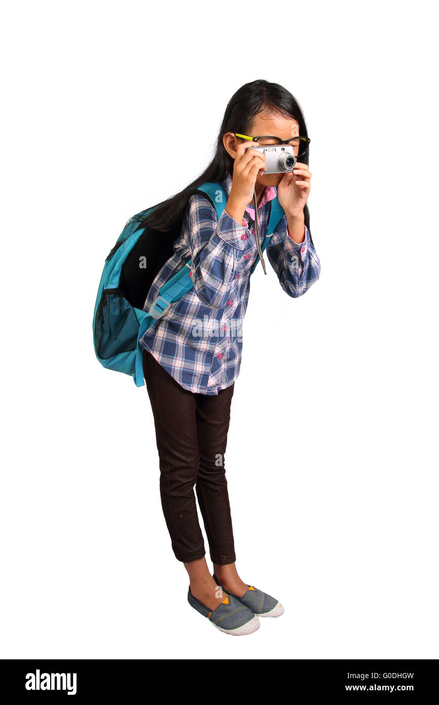 Kleines Mädchen mit Brille und Rucksack stehen und unter Foto mit ihrer Kamera isoliert auf weiss Stockfoto