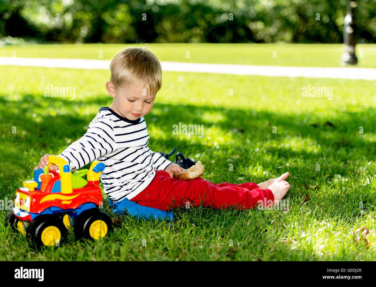 Vorschule junge spielt mit großen Spielzeugauto am Stadtpark Stockfoto