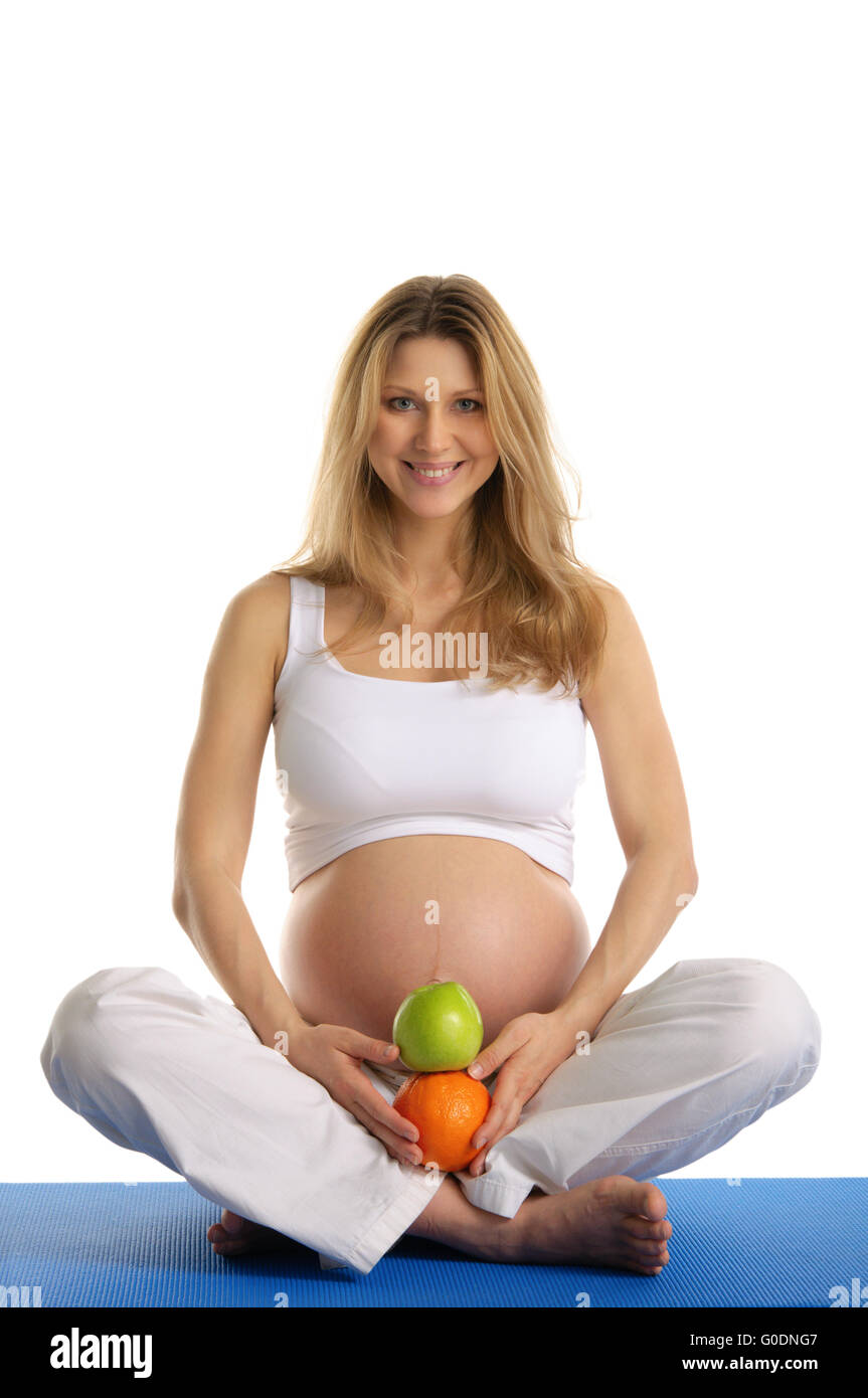 Schwangere Frau praktizieren Yoga und hält Obst Stockfoto