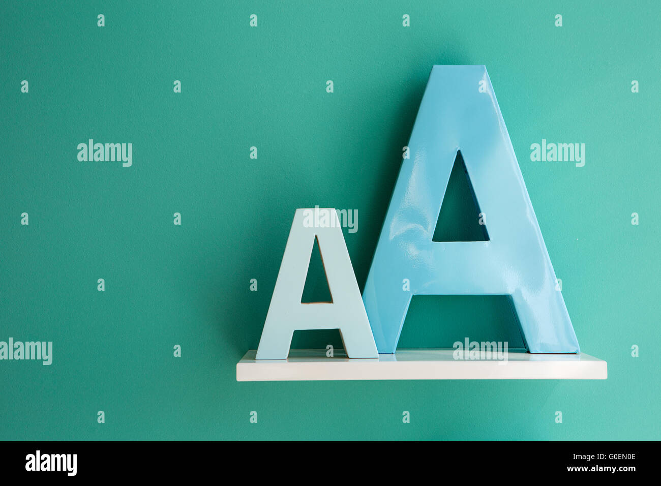Buchstaben "eine kleine und große Größe Türkis Farbe auf einem weißen Regal". Stockfoto