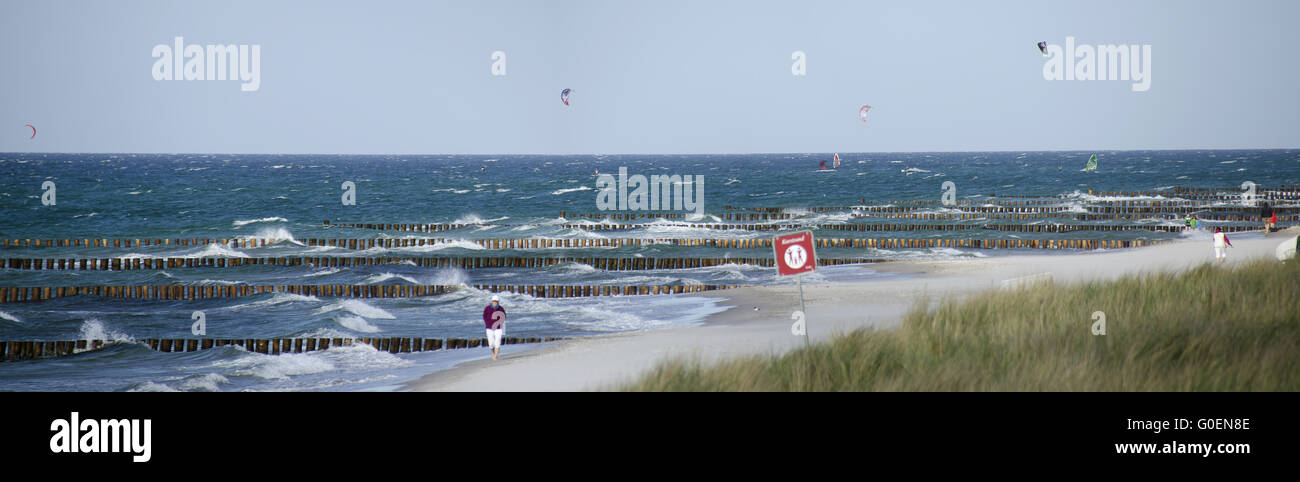 Sandstrand mit hölzernen Buhnen und Kitesurfer Stockfoto