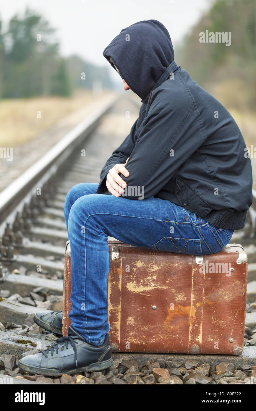 Teenager mit einem Koffer auf der Bahn im Regen Stockfoto