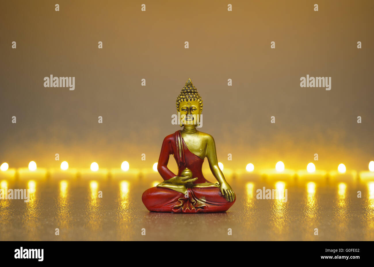 Buddha-Gestalt, die sitzen in der Meditation vor vielen Kerzen Stockfoto