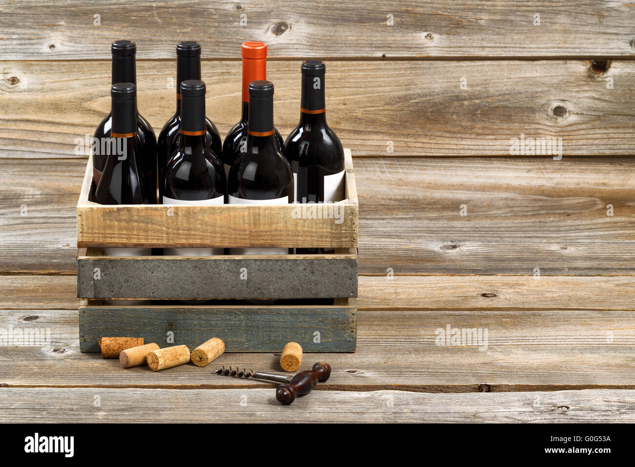 Flaschen Rotwein in Holzkiste auf urigen Holzbrettern Stockfoto