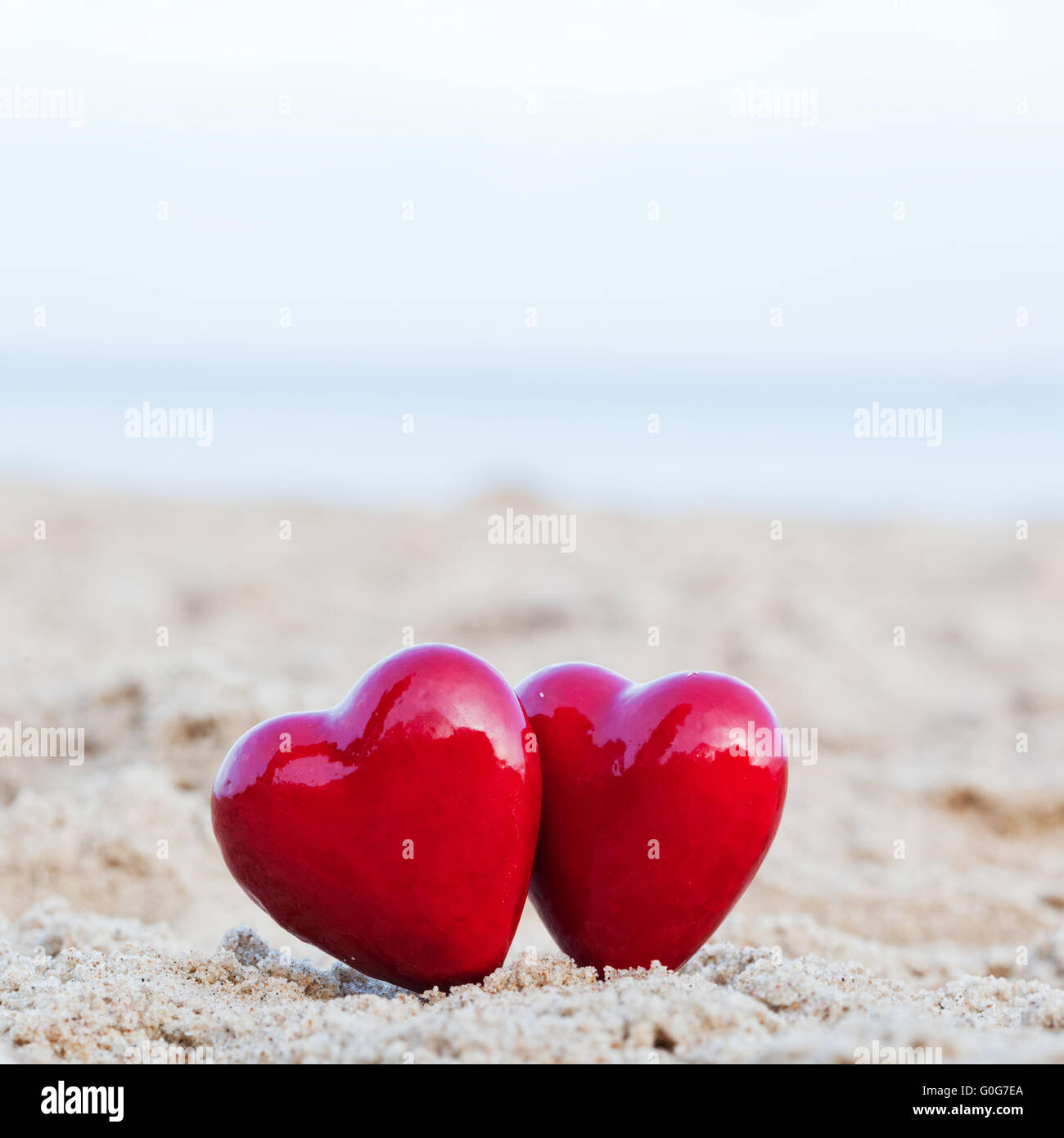 Zwei rote Herzen am Strand als Symbol für Liebe Stockfoto