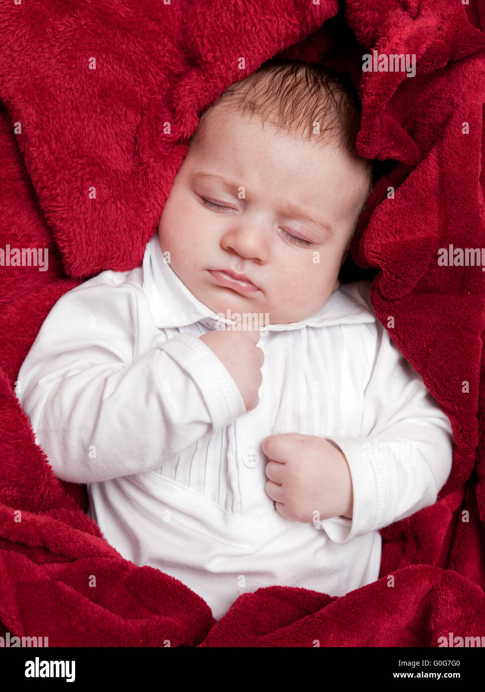 Schöne 3 Monate Baby schläft im Bett mit roten weichen Schneedecke bedeckt Stockfoto