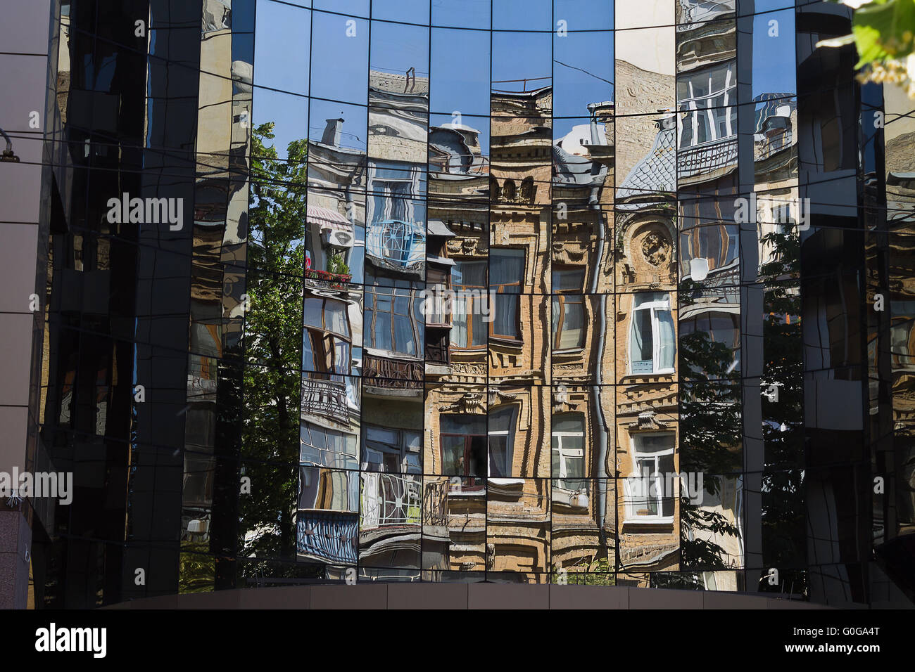 eine Reflexion eines alten Hauses in den Fenstern eines modernen Gebäudes Stockfoto