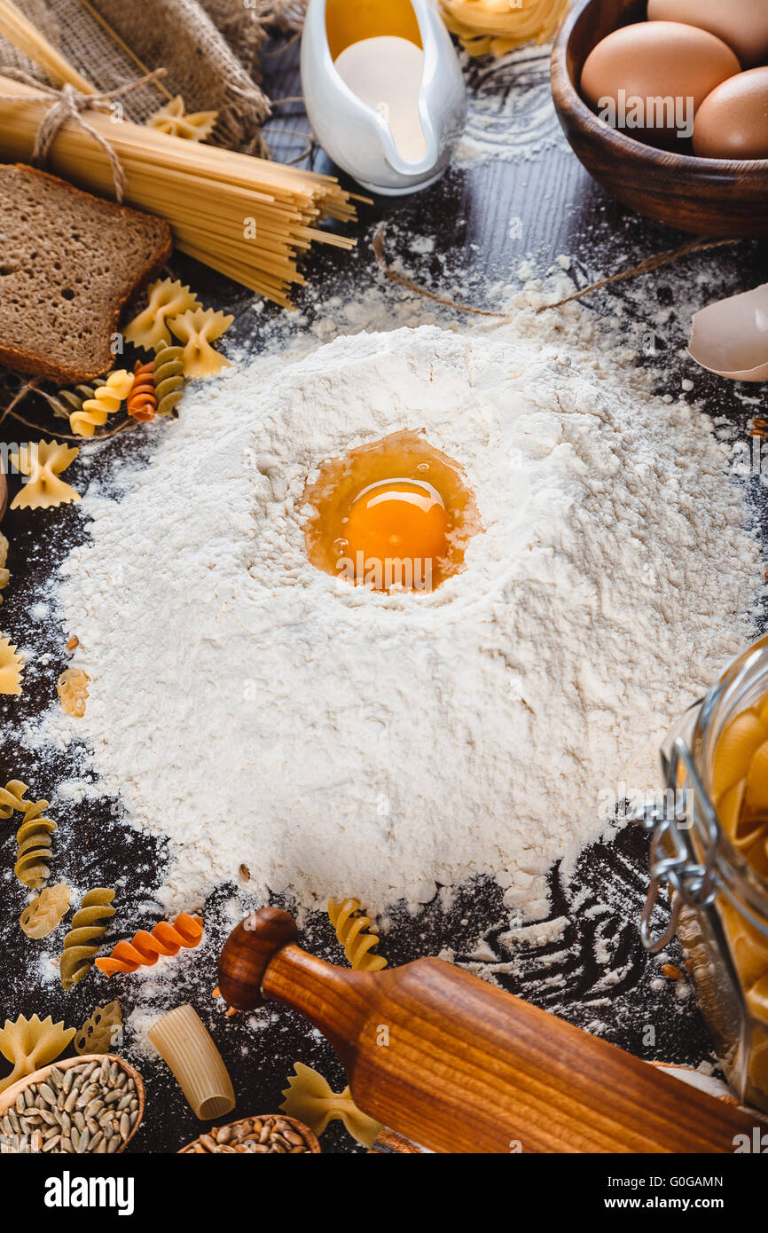 Nudeln auf dunklem Holz mit Eiern, Öl und Mehl Nahaufnahme Makro Stockfoto