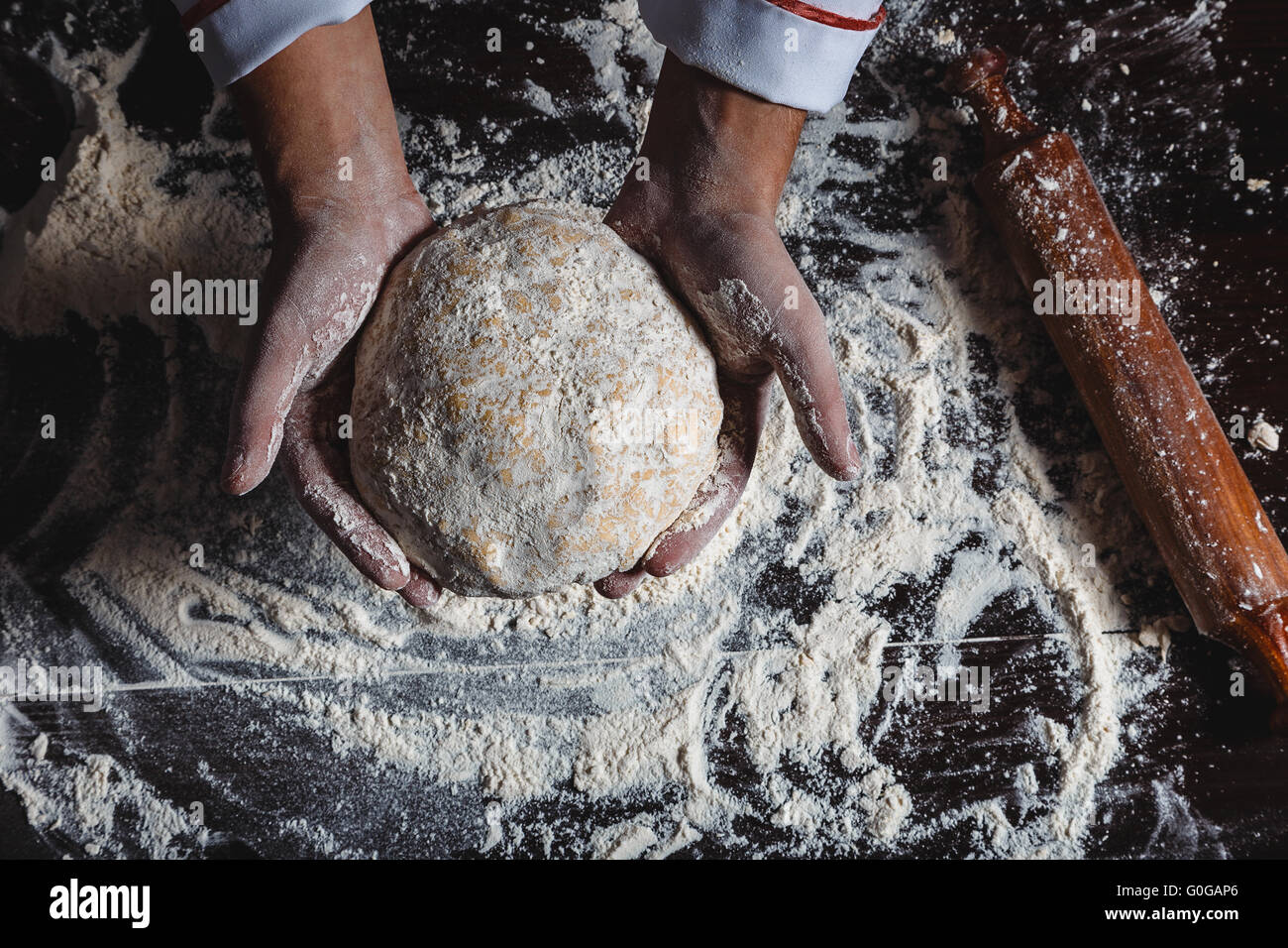 Cook #39; s Hände auf dunklem Holz mit Teig, Eiern, Öl und Mehl Nahaufnahme Makro Stockfoto