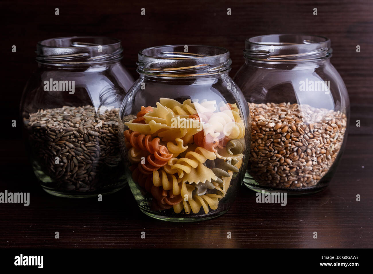 Pasta und trockenen Weizenkörner in einem Glas auf dunklem Holz Nahaufnahme Makro Stockfoto