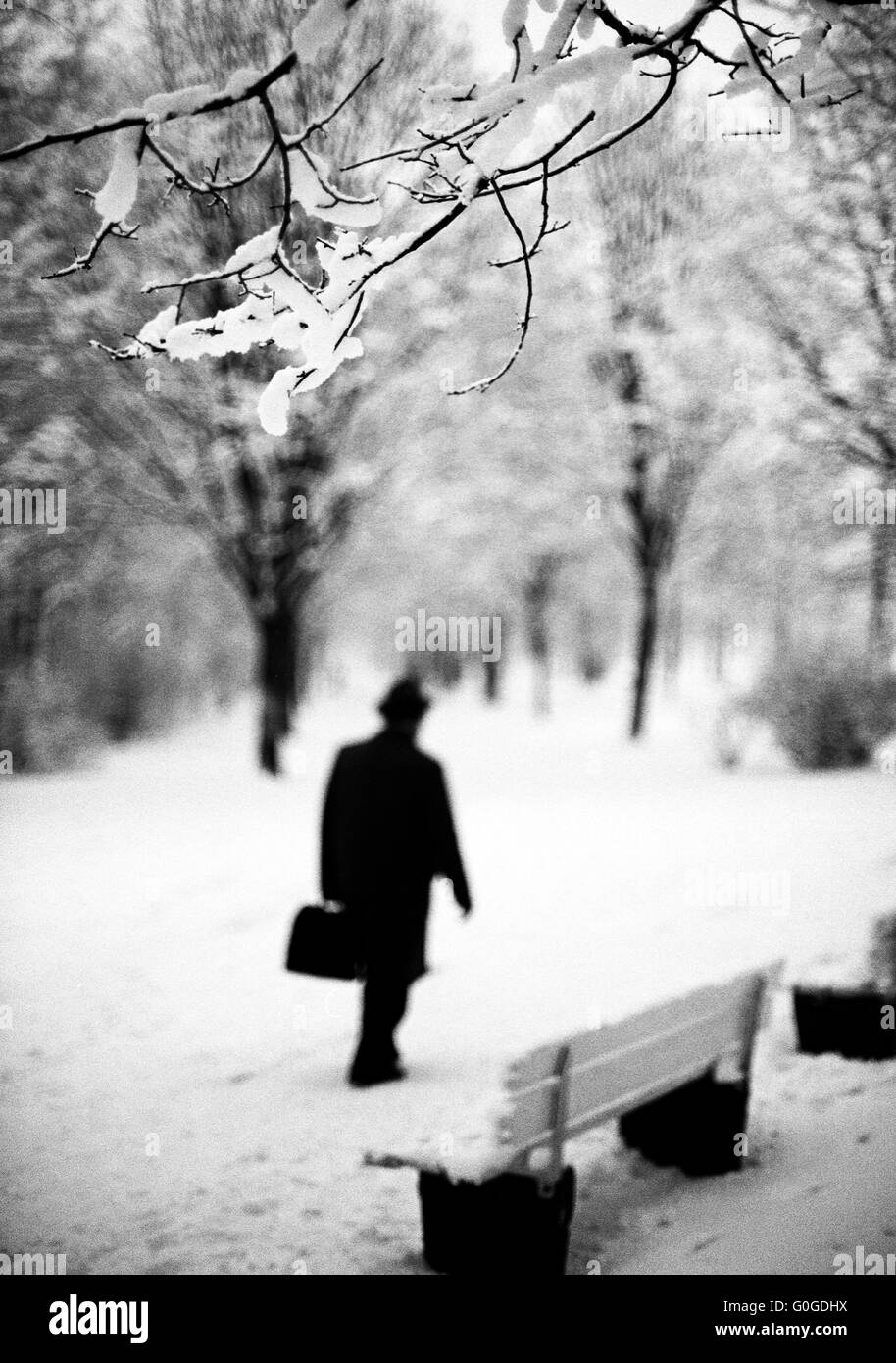 70er Jahre, Jahreszeiten, Winter, Schnee, Mann mit Hut und Winter Mantel zu Fuß in einem Park, Unschärfe, silhouette Stockfoto