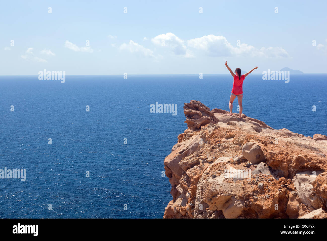 Glückliche Frau auf dem Felsen mit Hände hoch. Gewinner Stockfoto