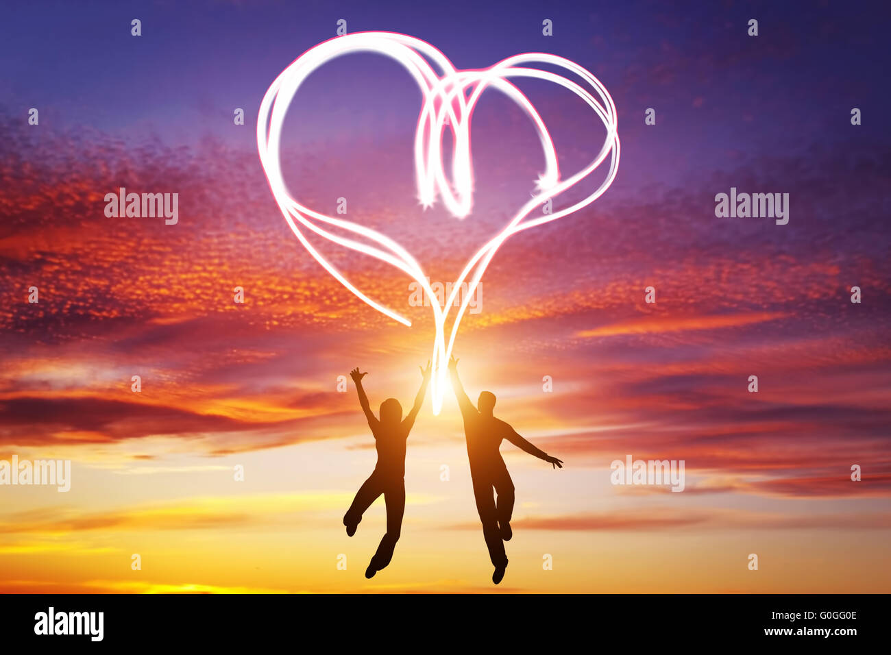 Glückliches Paar zusammen springen und machen ein Herz-Symbol des Lichts, die ihre Liebe zu manifestieren. Romantischer Sonnenuntergang Himmel Stockfoto