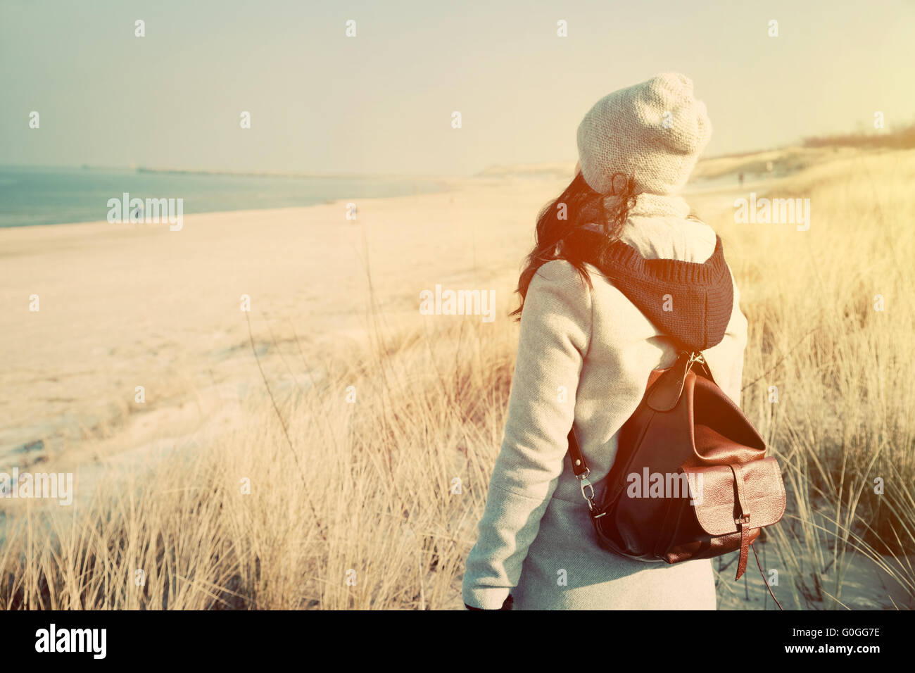Frau mit Retro-Rucksack stehen am Strand Stockfoto
