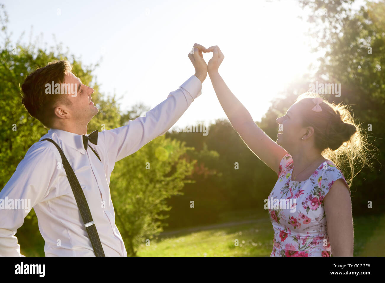 Paar in Liebe machen eine Herzform mit ihren Händen im Sonnenschein Stockfoto