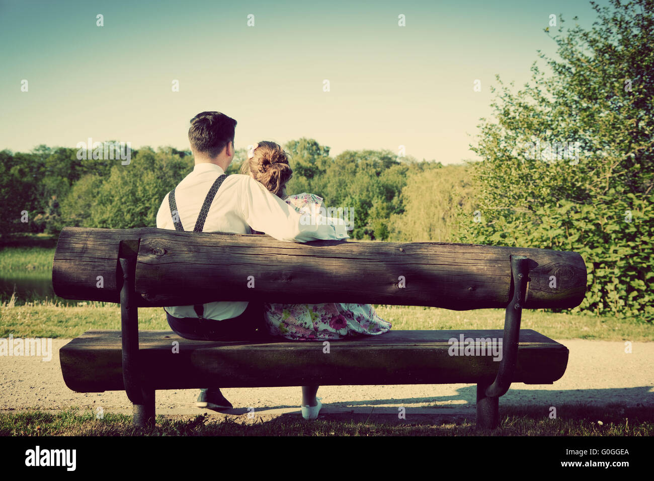 Junges Paar in Liebe sitzen auf einer Bank im Park. Jahrgang Stockfoto