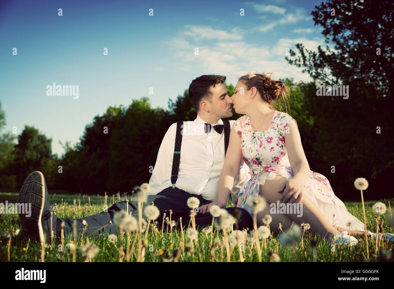 Romantisches Paar verliebt küssen auf dem Rasen sitzen. Jahrgang Stockfoto