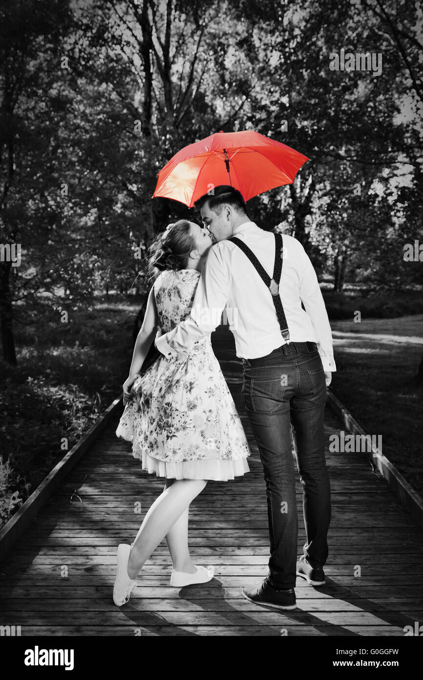 Junge romantische Paar in Liebe Flirten im Regen. Roten Regenschirm Stockfoto