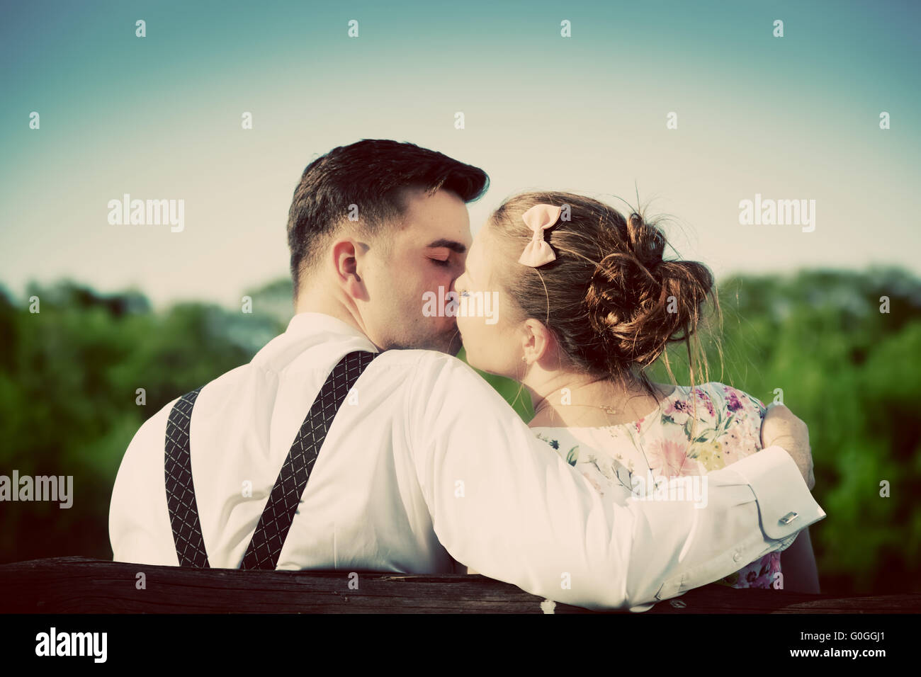 Junges Paar in Liebe küssen im Park auf einer Bank. Jahrgang. Stockfoto