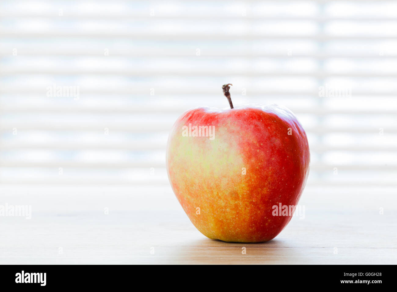 Reifer Apfel auf dem Tisch im Morgenlicht. Diät-Frühstück, gesunde Ernährung Stockfoto