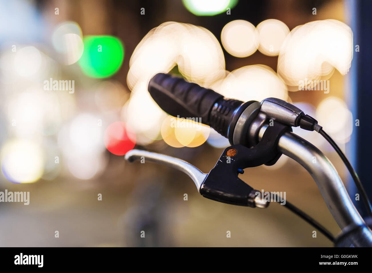 Ein Fahrradlenker mit einer Handbremse im Gegenlicht des Anzeigefensters. Nachtaufnahme. Stockfoto