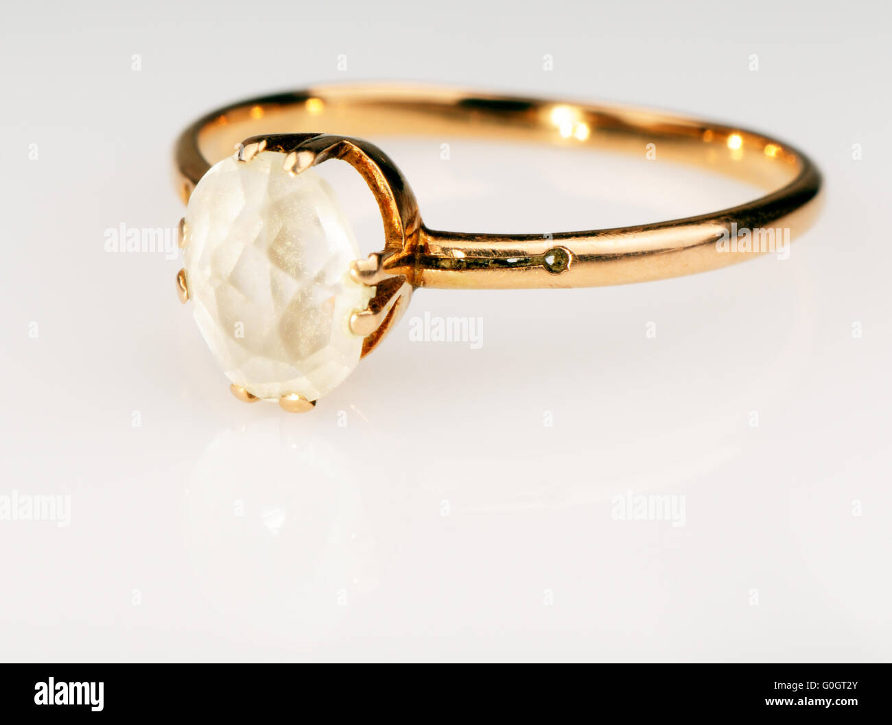 Goldener Fingerring mit Edelstein an weißen Spiegelfläche Stockfoto
