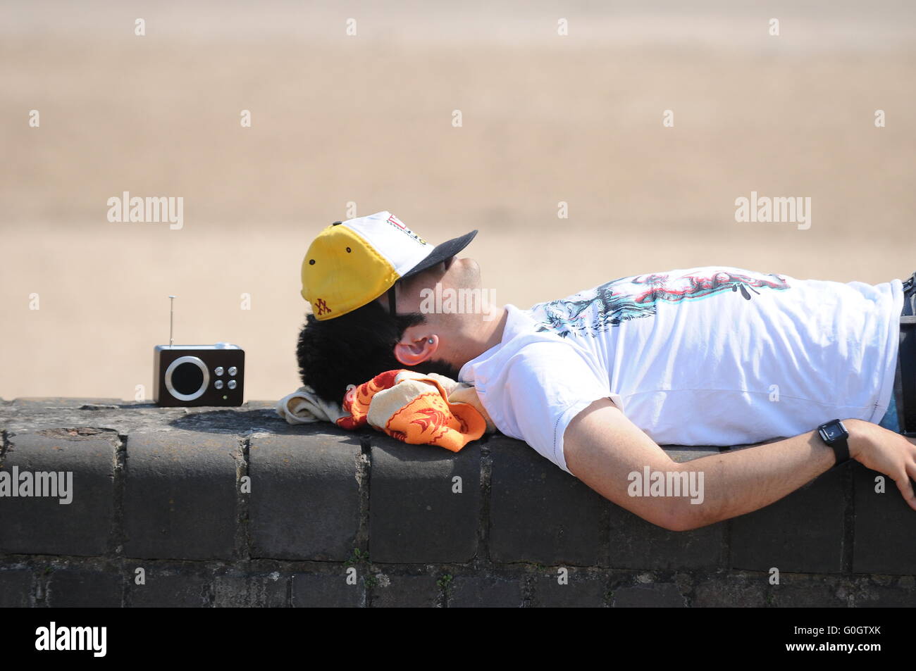 Ein Student Sonnenbaden an eine Mauer während der warmen sonnigen Sommerwetter. Stockfoto