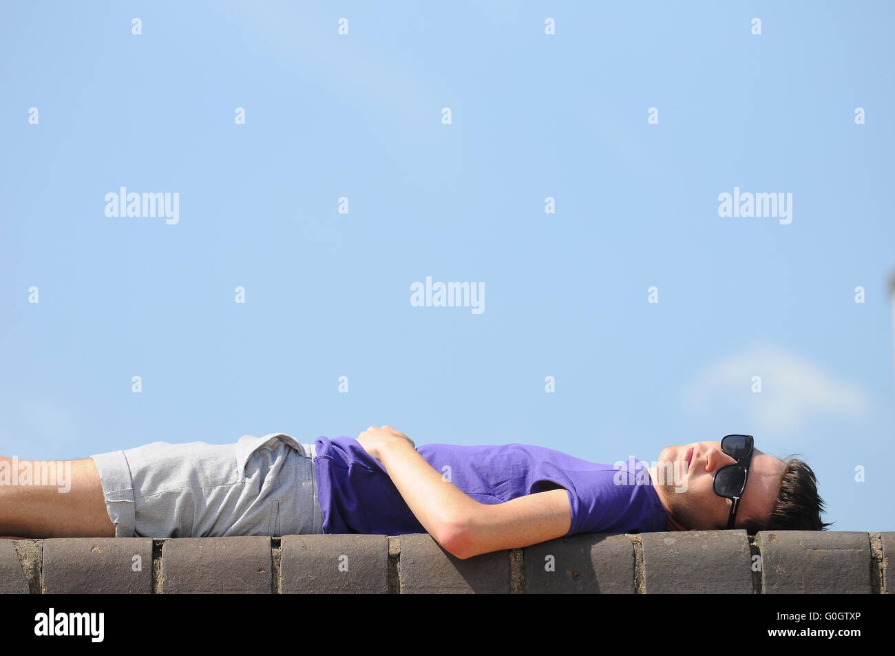 Ein Student Sonnenbaden an eine Mauer während der warmen sonnigen Sommerwetter. Stockfoto