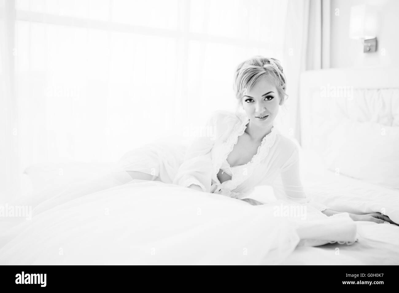 sanfte blonde Braut auf Couch mit Brautkleid Stockfoto