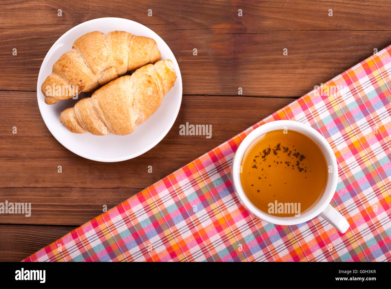 Croissant und eine Tasse Tee auf dem Küchentisch. Ansicht von oben. Stockfoto