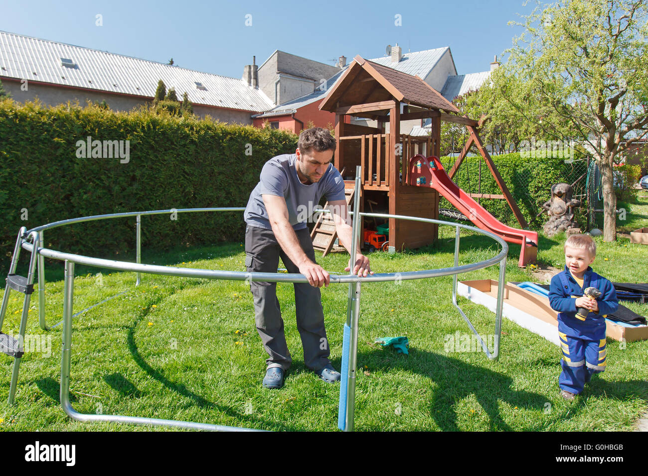 Vater und Sohn bei der Installation von großen Garten Trampoline. Bau von privaten Spielplatz. der Arbeitnehmer und sein kleiner Helfer. Stockfoto