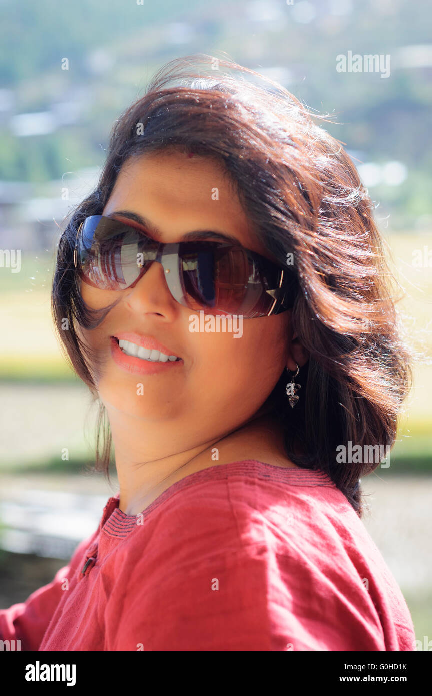 Porträt eines Reifen, asiatische, nicht-kaukasischen, Bengali schönen Lächeln auf den Lippen, jovial Dame mit Kopie Raum tragen rote Kleid und Hintergrundbeleuchtung Stockfoto
