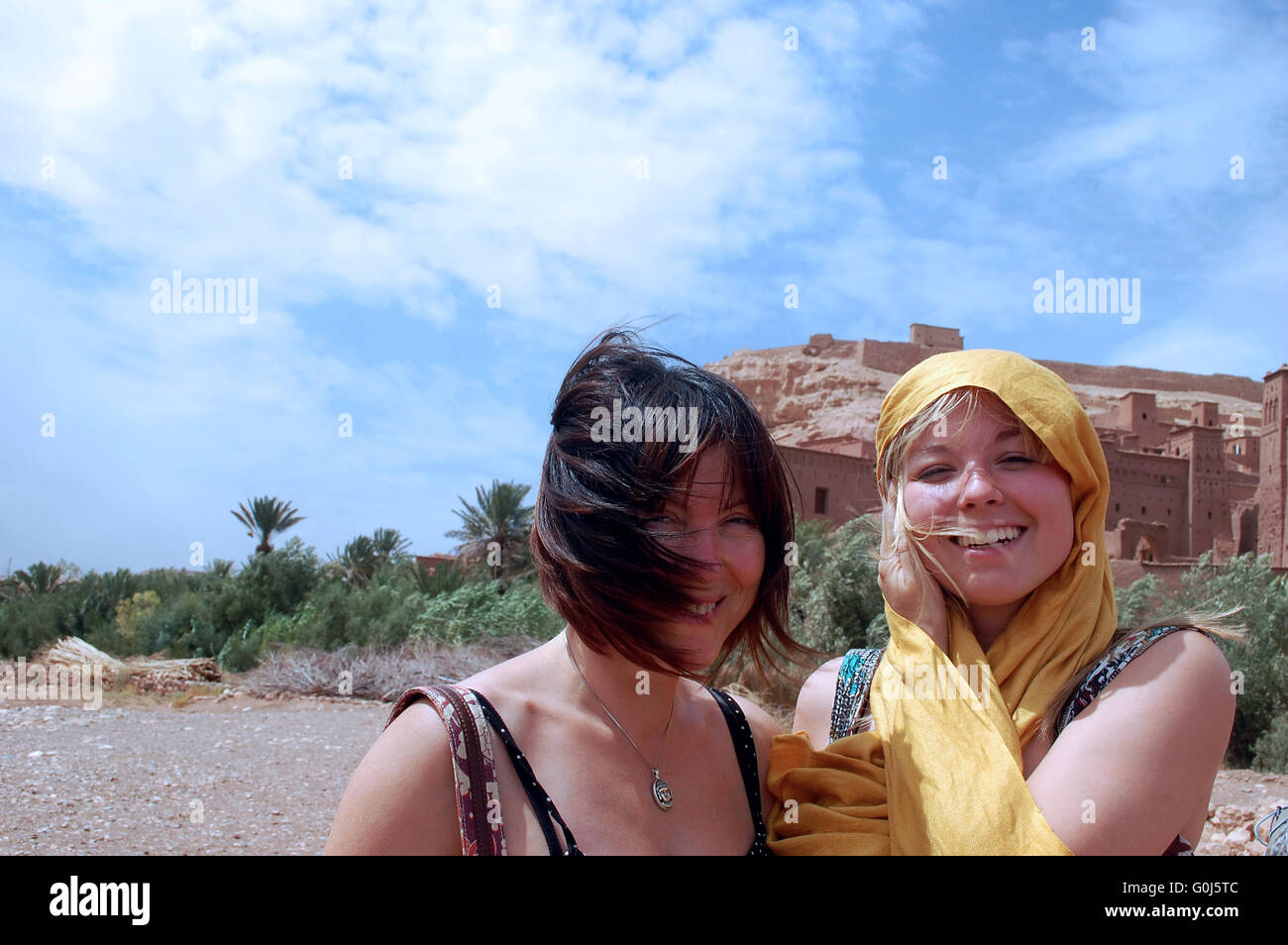 Zwei westliche Frauen posieren vor dem Hintergrund der La Casbah d'Ait Ben Haddou, die Lage in Marokko, wo viele Filme gedreht wurden Stockfoto