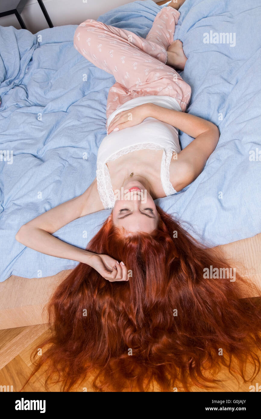 Frau liegend auf dem Bett mit Haare hängen über den Rand Stockfoto