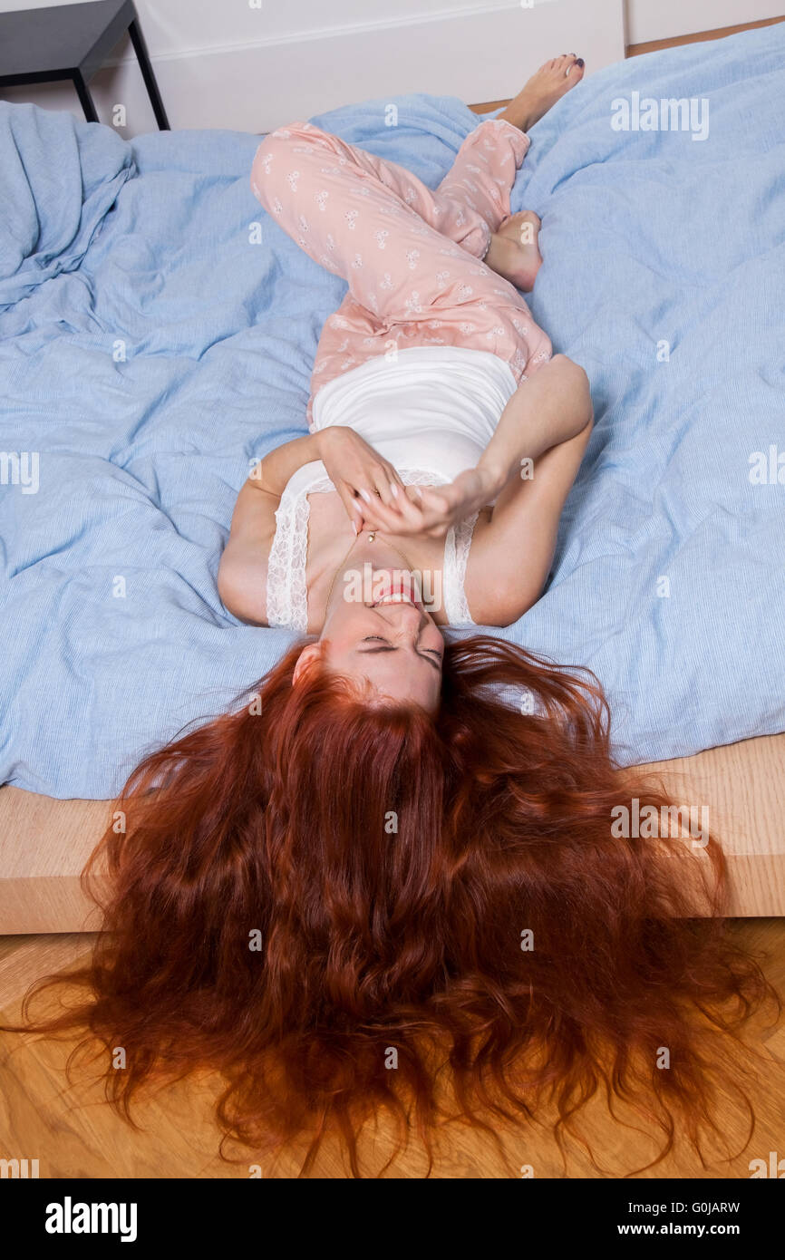 Frau liegend auf dem Bett mit Haare hängen über den Rand Stockfoto